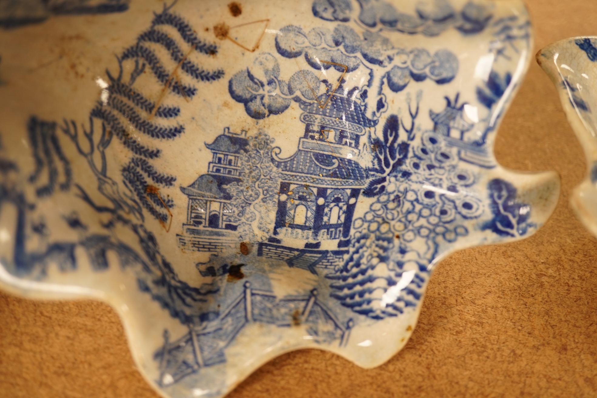 Two late 18th century Worcester or Caughley Cormorant fisherman pattern leaf pickle dishes and two early 19th century blue and white pottery leaf pickle dishes, largest 14.5cm long.